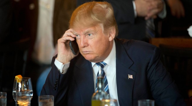 FILE - In this Feb. 18, 2016 file photo, Republican presidential candidate Donald Trump listens to his mobile phone during a lunch stop in North Charleston, S.C. Trump’s approach to Twitter has been as unorthodox as his presidential campaign.The billionaire’s use of the social media service has been unpredictable and unfiltered, sometimes brilliant and occasionally typographically challenged. He has celebrated the support of scores of accounts that appear almost solely dedicated to him. (AP Photo/Matt Rourke, File)