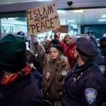 Protesters are surrounded by police officers and travelers as they pass through an exit of Terminal 4 at John F. Kennedy International Airport in New York, Saturday, Jan. 28, 2017 after earlier in the day two Iraqi refugees were detained while trying to enter the country. On Friday, Jan. 27, President Donald Trump signed an executive order suspending all immigration from countries with terrorism concerns for 90 days. Countries included in the ban are Iraq, Syria, Iran, Sudan, Libya, Somalia and Yemen, which are all Muslim-majority nations. (AP Photo/Craig Ruttle)