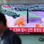 A man walks by a TV screen showing a local news program reporting about North Korea's missile firing at Seoul Train Station in Seoul, South Korea, Wednesday, July 5, 2017. North Korea's leader Kim Jong Un vowed his nation would "demonstrate its mettle to the U.S." and never put its weapons programs up for negotiations a day after test-launching its first intercontinental ballistic missile. The hard line suggests more tests are being prepared as the country tries to perfect a nuclear missile capable of striking anywhere in the United States. The letters read "North Korea, release an ICBM launching video." (AP Photo/Lee Jin-man)