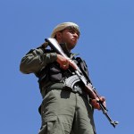 A Syrian Internal Security Forces soldier, stand guards as his comrades attend their  graduation ceremony, at Ain Issa desert base, in Raqqa province, northeast Syria, Thursday, July 20, 2017. Some 250 residents of Syria's Raqqa province are the latest batch to graduate from a brief U.S-training course that is preparing an internal security force to hold and secure areas as they are captured from Islamic State militants.(AP Photo/Hussein Malla)