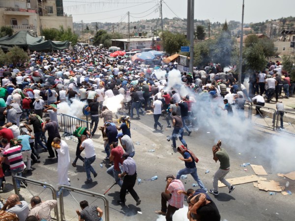 Palestinians run away from tear gas thrown by Israeli police officers outside Jerusalem's Old City, Friday, July 21, 2017. Israel police severely restricted Muslim access to a contested shrine in Jerusalem’s Old City on Friday to prevent protests over the installation of metal detectors at the holy site.. (AP Photo/Mahmoud Illean)