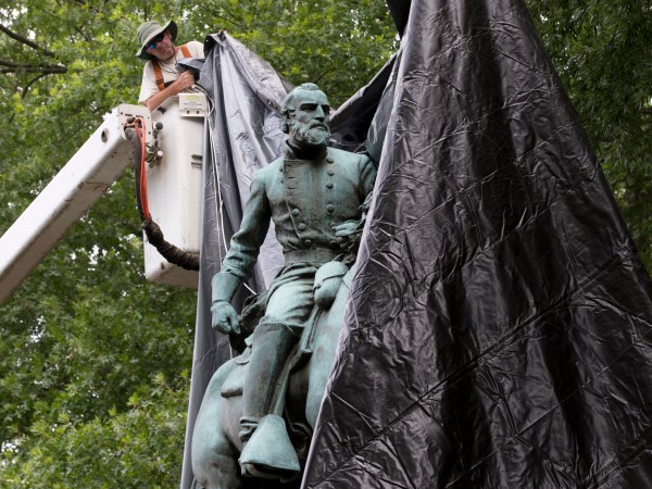 City workers drop a tarp over the statue of Confederate General Stonewall Jackson in Justice park in Chrlottesville, Va., Wednesday, Aug. 23, 2017.  The move intended to symbolize the city's mourning for a woman killed while protesting a white nationalist rally earlier this month. (AP Photo/Steve Helber)