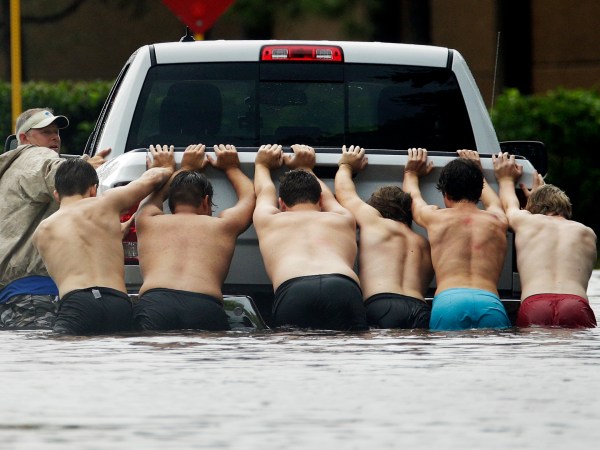 People push a stalled pickup to through a flooded street in Houston, Texas after Tropical Storm Harvey dumped heavy rains northeast Texas Sunday, Aug. 27, 2017. (AP Photo/Charlie Riedel)