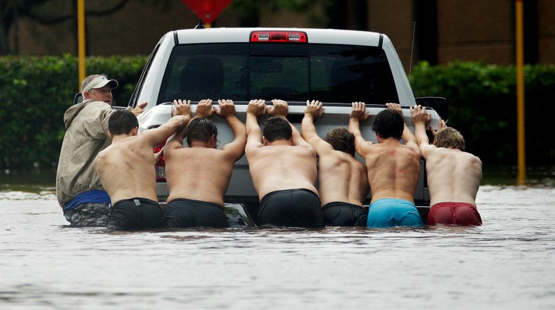 People push a stalled pickup to through a flooded street in Houston, Texas after Tropical Storm Harvey dumped heavy rains northeast Texas Sunday, Aug. 27, 2017. (AP Photo/Charlie Riedel)