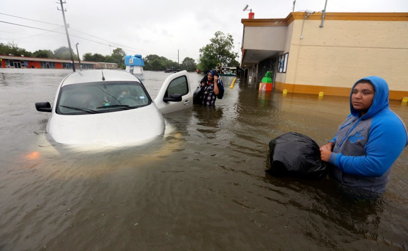 Conception Casa, center, and his friend Jose Martinez, right, check on Rhonda Worthington after her car become stuck in rising floodwaters from Tropical Storm Harvey in Houston, Texas, Monday, Aug. 28, 2017. The two men were evacuating from their home that had become flooded when they encountered Worthington's car floating off the road. (AP Photo/LM Otero)