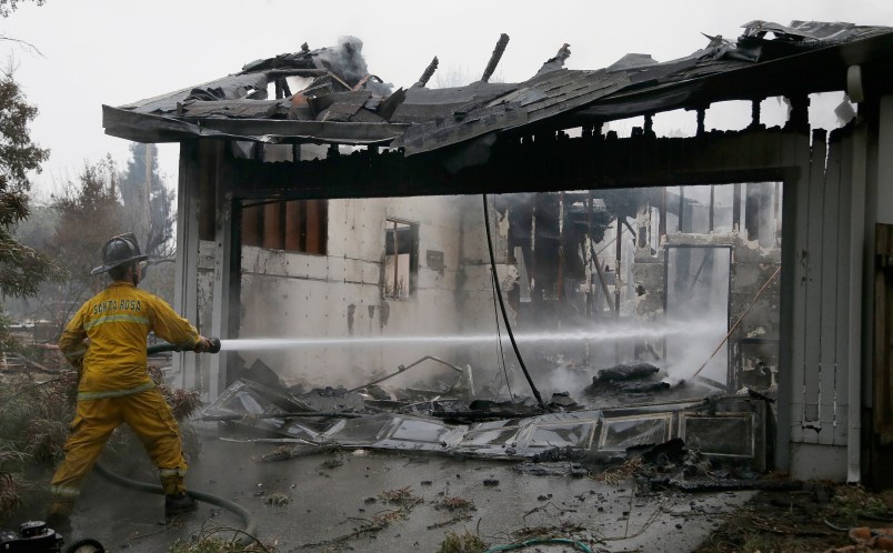 A Santa Rosa firefighter hoses down a hotspot in the Coffey Park area of Santa Rosa, Calif., on Tuesday, Oct. 10, 2017, An onslaught of wildfires across a wide swath of Northern California broke out almost simultaneously then grew exponentially, swallowing up properties from wineries to trailer parks and tearing through both tiny rural towns and urban subdivisions. (AP Photo/Ben Margot)