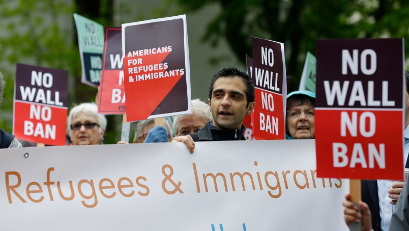 FILE--In this May 15, 2017, file photo, protesters hold signs during a demonstration against President Donald Trump's revised travel ban, Monday, May 15, 2017, outside a federal courthouse in Seattle. A three-judge panel of the 9th U.S. Circuit Court of Appeals on Monday upheld a decision to block the revised travel ban, which would suspend the nation's refugee program and temporarily bar new visas for citizens of Iran, Libya, Somalia, Sudan, Syria and Yemen. (AP Photo/Ted S. Warren, file)