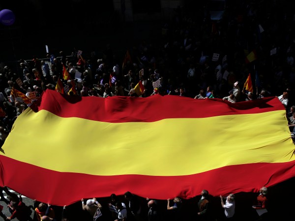 People hold a Spanish flag as they march during a protest the regional Catalan government's push to break away from the rest of Spain in Barcelona, Spain, Sunday, March 19, 2017. Several protesters carried Spanish flags and signs saying "Stop the Coup"  a reference to the regional government's plan to hold a referendum on independence, which Spain says is unconstitutional. (AP Photo/Manu Fernandez)