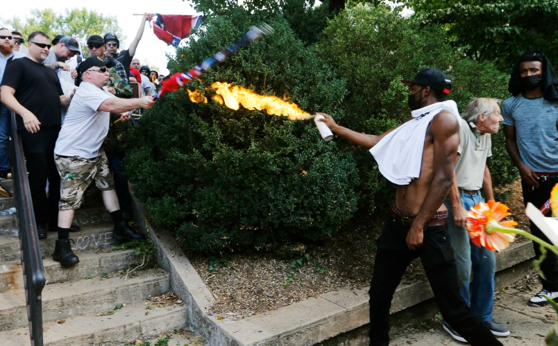 A counter demonstrator uses a lighted spray can against a white nationalist demonstrator at the entrance to Lee Park in Charlottesville, Va., Saturday, Aug. 12, 2017.   Gov. Terry McAuliffe declared a state of emergency and police dressed in riot gear ordered people to disperse after chaotic violent clashes between white nationalists and counter protestors. (AP Photo/Steve Helber)