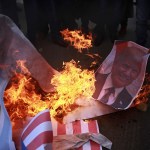 Palestinian protesters burn a poster of U.S. President Donald Trump and mocks of Israeli and American flags, during a protest against US decision to recognize Jerusalem as Israel’s capital, in Gaza City Thursday, Dec. 7, 2017. (AP Photo/ Khalil Hamra)