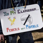 SANTA FE, NM - MARCH 24, 2018:  A school teacher wears a sign around his neck expressing his opposition to arming teachers during a 'March For Our Lives' rally in Santa Fe, New Mexico. The rally and march, part of a nationwide series of similar events in response to school shootings, brought together gun control advocates urging legislation to reduce gun violence and the sale and public ownership of assault rifles in the United States. (Photo by Robert Alexander/Getty Images)