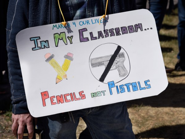 SANTA FE, NM - MARCH 24, 2018:  A school teacher wears a sign around his neck expressing his opposition to arming teachers during a 'March For Our Lives' rally in Santa Fe, New Mexico. The rally and march, part of a nationwide series of similar events in response to school shootings, brought together gun control advocates urging legislation to reduce gun violence and the sale and public ownership of assault rifles in the United States. (Photo by Robert Alexander/Getty Images)