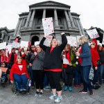 As viewed through a fisheye lens, Stephanie Rolf, a teacher in the Douglas County, Colo., school system, leads a cheer during a teacher rally Thursday, April 26, 2018, in Denver. More than 10,000 teachers in Colorado are expected to demonstrate as part of a burgeoning teacher uprising from the East to the interior West that is demanding more tax dollars be spent in public schools. (AP Photo/David Zalubowski)