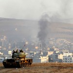 SANLIURFA, TURKEY -  OCTOBER 9: Turkish soldiers on a tank hold their positions on a hilltop in the outskirts of Suruc, Turkey, at the Turkey-Syria border, overlooking smoke rising from a strike in Kobani, Syria, during fighting between Syrian Kurds and the militants of Islamic State group, Thursday, Oct. 9, 2014. Kobani, also known as Ayn Arab, and its surrounding areas, has been under assault by extremists of the Islamic State group since mid-September and is being defended by Kurdish  fighters. (Photo by Gokhan Sahin/Getty Images)