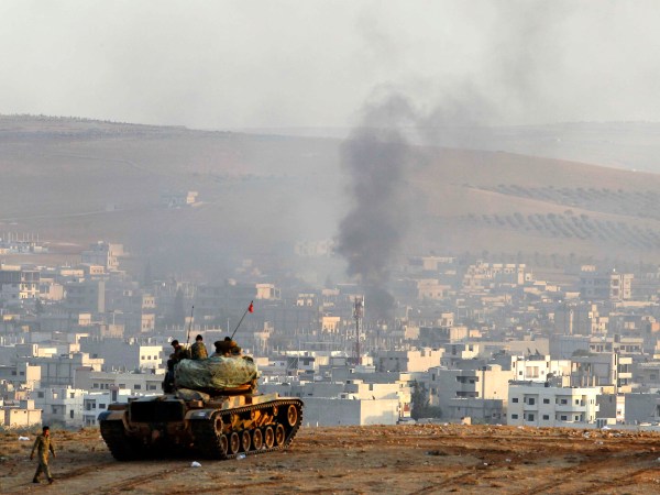SANLIURFA, TURKEY -  OCTOBER 9: Turkish soldiers on a tank hold their positions on a hilltop in the outskirts of Suruc, Turkey, at the Turkey-Syria border, overlooking smoke rising from a strike in Kobani, Syria, during fighting between Syrian Kurds and the militants of Islamic State group, Thursday, Oct. 9, 2014. Kobani, also known as Ayn Arab, and its surrounding areas, has been under assault by extremists of the Islamic State group since mid-September and is being defended by Kurdish  fighters. (Photo by Gokhan Sahin/Getty Images)