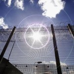 NORWICH, UNITED KINGDOM - AUGUST 25:  (EDITORS NOTE: IMAGES EMBARGOED FOR PUBLICATION UNTIL 0001GMT AUGUST 26, 2005; NATURAL LENS FLARE VISIBLE IN IMAGE) The sun shines through high security fencing surrounding Norwich Prison on August 25, 2005 in Norwich, England. A Chief Inspector of Prisons report on Norwich Prison says healthcare accommodation was among the worst seen, as prisoners suffered from unscreened toilets, little natural light, poor suicide prevention, inadequate education and training for long-term prisoners. (Photo by Peter Macdiarmid/Getty Images)