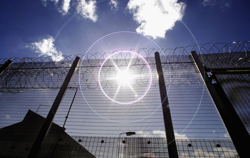 NORWICH, UNITED KINGDOM - AUGUST 25:  (EDITORS NOTE: IMAGES EMBARGOED FOR PUBLICATION UNTIL 0001GMT AUGUST 26, 2005; NATURAL LENS FLARE VISIBLE IN IMAGE) The sun shines through high security fencing surrounding Norwich Prison on August 25, 2005 in Norwich, England. A Chief Inspector of Prisons report on Norwich Prison says healthcare accommodation was among the worst seen, as prisoners suffered from unscreened toilets, little natural light, poor suicide prevention, inadequate education and training for long-term prisoners. (Photo by Peter Macdiarmid/Getty Images)