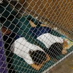 Two female detainees sleep in a holding cell, as the children are separated by age group and gender, as hundreds of mostly Central American immigrant children are being processed and held at the U.S. Customs and Border Protection Nogales Placement Center on Wednesday, June 18, 2014, in Nogales, Ariz.  CPB provided media tours Wednesday of two locations in Brownsville, Texas, and Nogales, that have been central to processing the more than 47,000 unaccompanied children who have entered the country illegally since Oct. 1. (AP Photo/Ross D. Franklin, Pool)