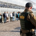 EMBARGOED UNTIL 10AM 6.5.2018Government agents stand guard alongside apprehended suspects during an immigration sting at Corso's Flower and Garden Center, Tuesday, June 5, 2018, in Castalia, Ohio. The operation is one of the largest against employers in recent years on allegations of violating immigration laws. It was expected to cast a net over hundreds of employees at two locations. (AP Photo/John Minchillo)