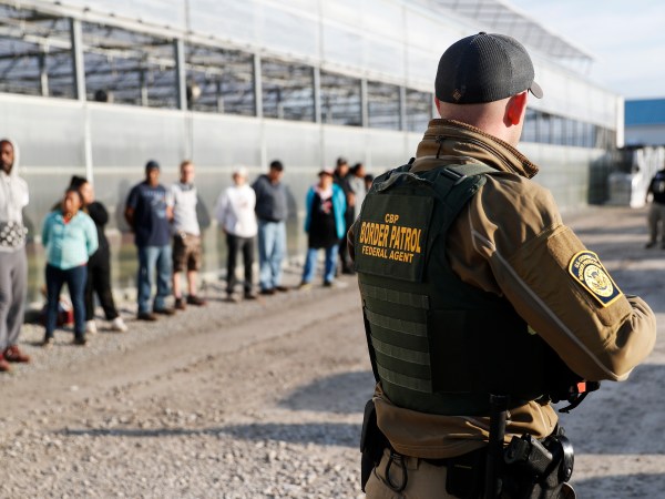 EMBARGOED UNTIL 10AM 6.5.2018Government agents stand guard alongside apprehended suspects during an immigration sting at Corso's Flower and Garden Center, Tuesday, June 5, 2018, in Castalia, Ohio. The operation is one of the largest against employers in recent years on allegations of violating immigration laws. It was expected to cast a net over hundreds of employees at two locations. (AP Photo/John Minchillo)