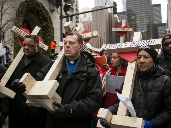 FILE -  In this Dec. 31, 2016 file photo, The Rev. Michael Pfleger, center, Rev. Jesse Jackson, left, and state Sen. Jacqueline Collins, right, led hundreds in a march down Michigan Avenue, carrying crosses for all those killed by Chicago violence in 2016 and to call for an end to violence in Chicago. Protesters planning to shut down a major Chicago interstate on Saturday, July 7, 2018, say they’re trying to increase pressure on public officials to address the gun violence that’s claimed hundreds of lives in some of the city’s poorest neighborhoods. (Ashlee Rezin/Chicago Sun-Times via AP)