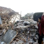 A man carries his belonging pass ruin houses at a village affected by Sunday's earthquake in North Lombok, Indonesia, Thursday, Aug. 9, 2018. The north of Lombok has been devastated by the magnitude 7.0 quake that struck Sunday night, damaging thousands of buildings and killing a large number of people. (AP Photo/Firdia Lisnawati)