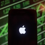 BANGKOK, THAILAND - 2018/07/30: An iPhone displays the Apple logo with a background of a market value increasing on the stock exchange behind. (Photo by Guillaume Payen/SOPA Images/LightRocket via Getty Images)