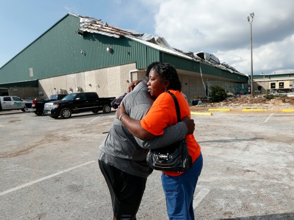 Franlisa Smith, whose son Nick Smith is a defensive lineman on the Mosley High football team, hugs defensive line coach William Mosley at the start of practice at the school, which was heavily damaged from Hurricane Michael, in Lynn Haven, Fla., Friday, Oct. 19, 2018. (AP Photo/Gerald Herbert)