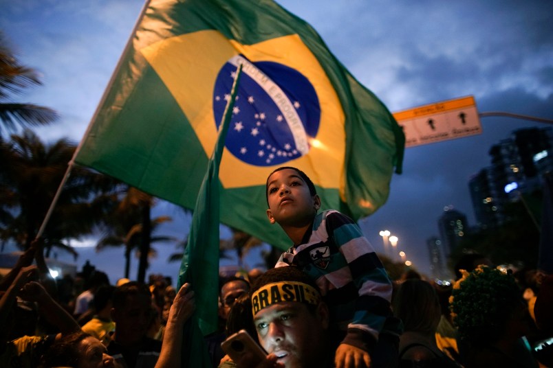 Supporters stand with is kid on the shoulders as he wait for the speech of Jair Bolsonaro in front of his residence in Rio de Janeiro, Brazil, Sunday, Oct. 28, 2018. Brazil’s Supreme Electoral Tribunal declared the far-right congressman the next president of Latin America’s biggest country. (AP Photo/Leo Correa)