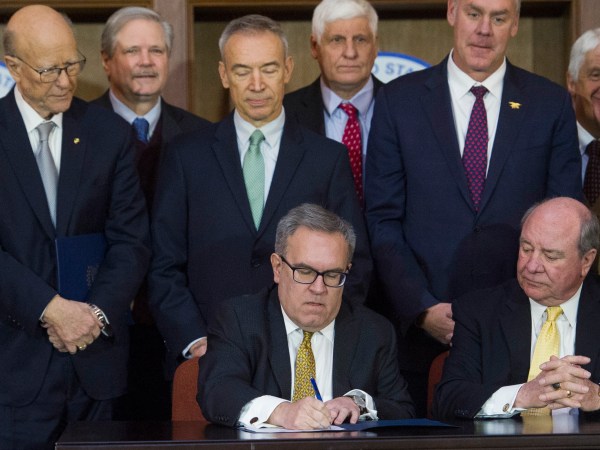 Acting EPA Administrator Andrew Wheeler, seated left, signs an order withdrawing federal protections for countless waterways and wetlands, as Assistant Secretary of the Army for Civil Works Rickey "RD" James, seated right, looks on, at EPA headquarters in Washington, Tuesday, Dec. 11, 2018. Look on behind are Senate Agriculture Committe Chairman Pat Ross, R-Kansas, left, and Secretary of the Interior Ryan Zinke, second from right.   (AP Photo/Cliff Owen)