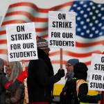 Teachers carry placards as they walk a picket line outside South High School early Monday, Feb. 11, 2019, in Denver. The walkout is the first for teachers in Denver since 1994 and centers on base pay. (AP Photo/David Zalubowski)