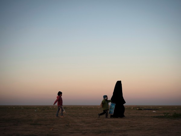 A woman walks with her children at a U.S.-backed Syrian Democratic Forces (SDF) screening area after being evacuated out of the last territory held by Islamic State militants, in the desert outside Baghouz, Syria, Friday, March 1, 2019. (AP Photo/Felipe Dana)