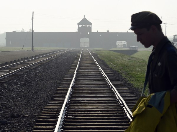 FILE - In this file photo dated Friday, July 29, 2016, a man crosses the iconic rails leading to the former Nazi death camp of Auschwitz-Birkenau prior to a visit by Pope Francis, in Poland. The Polish government approved a new bill on Tuesday Aug. 16, 2016, that foresees prison terms for anyone who uses phrases like "Polish death camps" to refer to camps like Auschwitz that Nazi Germany operated in occupied Poland during World War II, because they are not Polish but Nazi camps, Justice Minister Zbignew Ziobro said Tuesday.  (AP Photo/Alik Keplicz, FILE)