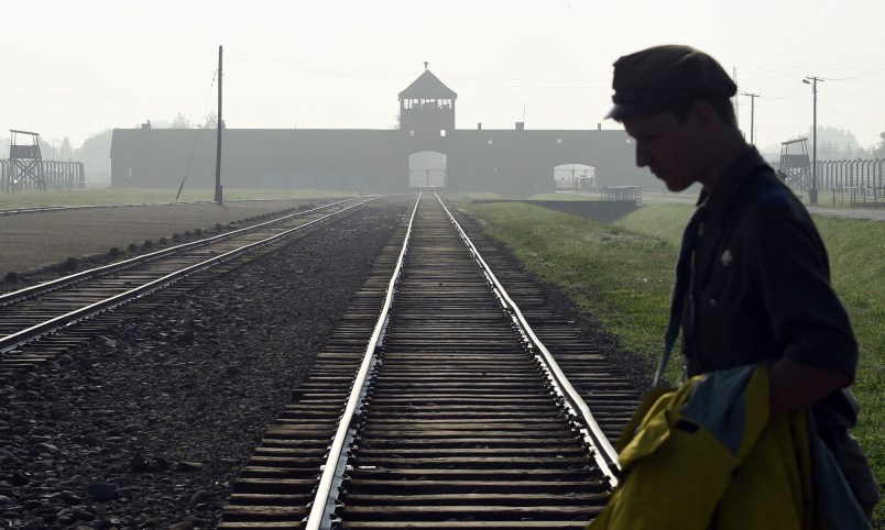 FILE - In this file photo dated Friday, July 29, 2016, a man crosses the iconic rails leading to the former Nazi death camp of Auschwitz-Birkenau prior to a visit by Pope Francis, in Poland. The Polish government approved a new bill on Tuesday Aug. 16, 2016, that foresees prison terms for anyone who uses phrases like "Polish death camps" to refer to camps like Auschwitz that Nazi Germany operated in occupied Poland during World War II, because they are not Polish but Nazi camps, Justice Minister Zbignew Ziobro said Tuesday.  (AP Photo/Alik Keplicz, FILE)