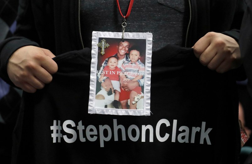 A mourner holds up a photo of police shooting victim Stephon Clark during the funeral services for Clark at Bayside Of South Sacramento Church in Sacramento, Calif., Thursday, March 29, 2018. Clark, who was unarmed, was shot and killed by Sacramento Police Officers, Sunday, March 18, 2018. (AP Photo/Jeff Chiu, Pool)