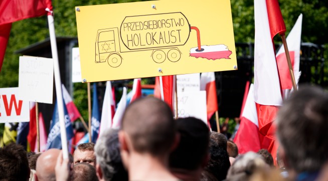 A sign is seen during the protest against the JUST act in Warsaw, Poland on May 11, 2019. Several thousand people gathered in front of the Prime Minister's office and marched to the US embassy to protest the Justice for Uncompensated Survivors Today (JUST) act 447 which requires the US State Department to report on progress made by 47 countries on compensation of assests seized during WWII for Holocaust survivors. Poland is the only European country that has not yet passed any laws to regulate compensation for rightful owners of seized properties. (Photo by Jaap Arriens/NurPhoto)