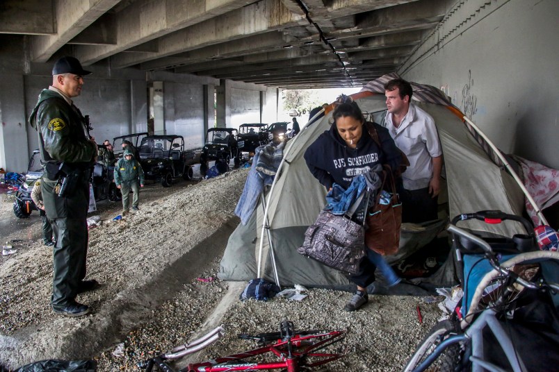 PICO RIVERA, CA JANUARY 05, 2016 ---  Los Angeles sheriff deputy Michael Galvan, left, warns a couple living under Freeway 5 bridge along San Gabriel River in Pico Rivera. LASD deputies ventured out in pouring rain looking for homeless encampments along river to warn inhabitants  about danger of flooding and to provide them information of nearby shelters. (Irfan Khan / Los Angeles Times)