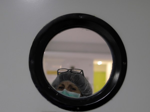 A health worker wearing a face mask looks out of from a window at a nursing homes in Madrid, Spain, Tuesday, March 31, 2020. The new coronavirus causes mild or moderate symptoms for most people, but for some, especially older adults and people with existing health problems, it can cause more severe illness or death. (AP Photo/Manu Fernandez)