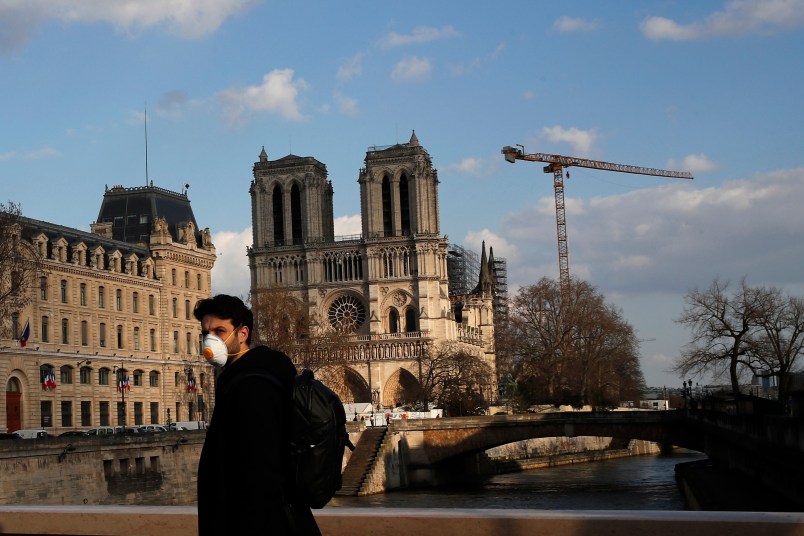 A masked man walks next to Notre Dame Cathedral, in Paris, Wednesday, March 18, 2020. French President Emmanuel Macron said that for 15 days people will be allowed to leave the place they live only for necessary activities such as shopping for food, going to work or taking a walk. For most people, the new coronavirus causes only mild or moderate symptoms. For some it can cause more severe illness, especially in older adults and people with existing health problems. (AP Photo/Francois Mori)