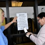 Carol Talkington helps Terri Bonasso tape a notice on the Emergency room door following a vigil at the closing of Fairmont Regional Medical Center on March 19, 2020.