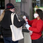 Supermarket employees distribute protective masks to customers in Vienna, Austria, Wednesday, April 1, 2020. In Austria protective masks should be worn in shops from Wednesday on. The Austrian government has moved to restrict freedom of movement for people, in an effort to slow the onset of the COVID-19 coronavirus. The new coronavirus causes mild or moderate symptoms for most people, but for some, especially older adults and people with existing health problems, it can cause more severe illness or death. (AP Photo/Ronald Zak)