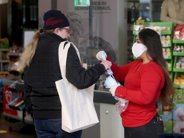 Supermarket employees distribute protective masks to customers in Vienna, Austria, Wednesday, April 1, 2020. In Austria protective masks should be worn in shops from Wednesday on. The Austrian government has moved to restrict freedom of movement for people, in an effort to slow the onset of the COVID-19 coronavirus. The new coronavirus causes mild or moderate symptoms for most people, but for some, especially older adults and people with existing health problems, it can cause more severe illness or death. (AP Photo/Ronald Zak)