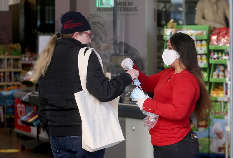 Supermarket employees distribute protective masks to customers in Vienna, Austria, Wednesday, April 1, 2020. In Austria protective masks should be worn in shops from Wednesday on. The Austrian government has moved to restrict freedom of movement for people, in an effort to slow the onset of the COVID-19 coronavirus. The new coronavirus causes mild or moderate symptoms for most people, but for some, especially older adults and people with existing health problems, it can cause more severe illness or death. (AP Photo/Ronald Zak)