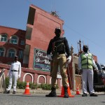 Police officers stand guard outside a mosque during a lockdown to contain the coronavirus in Karachi, Pakistan, Friday, March, 3, 2020. Some mosques were allowed to remain open in Pakistan on Friday, the Muslim sabbath when adherents gather for weekly prayers, even as the coronavirus pandemic spread and much of the country had shut down. (AP Photo/Fareed Khan)