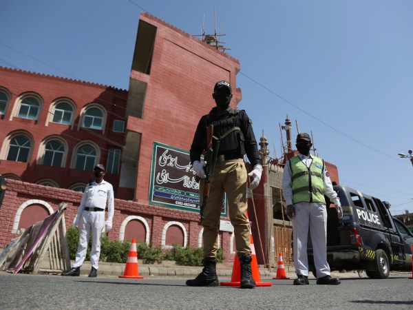 Police officers stand guard outside a mosque during a lockdown to contain the coronavirus in Karachi, Pakistan, Friday, March, 3, 2020. Some mosques were allowed to remain open in Pakistan on Friday, the Muslim sabbath when adherents gather for weekly prayers, even as the coronavirus pandemic spread and much of the country had shut down. (AP Photo/Fareed Khan)