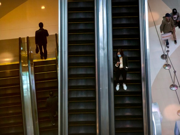 A woman wears a face mask to protect against the spread of the new coronavirus as she rides an escalator at a shopping mall in Beijing, Wednesday, April 15, 2020. China reported several dozen new coronavirus cases on Wednesday, mostly from overseas. (AP Photo/Mark Schiefelbein)