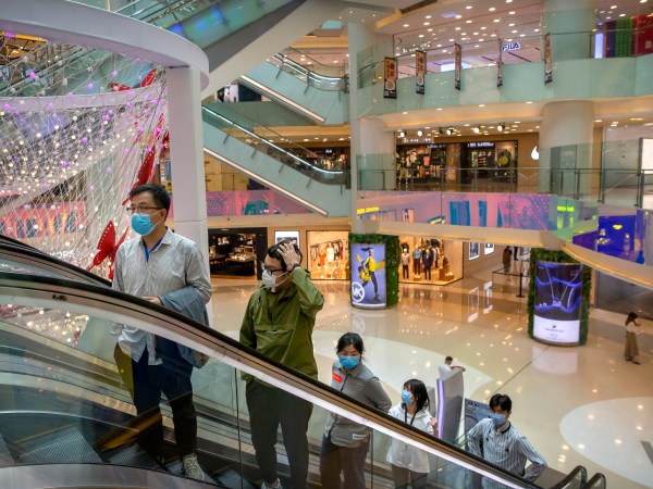 ***HOLD FOR CHINA GDP STORY***In this April 15, 2020 photo, people wear facemasks to protect against the spread of the new coronavirus cleans as they ride an escalator at a shopping mall in Beijing. (AP Photo/Mark Schiefelbein)