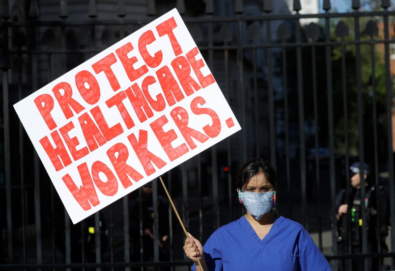 Doctor Meenal Viz holds a banner as she protests outside Downing Street in London, as the country is in lockdown to help curb the spread of the coronavirus, Sunday, April 19, 2020. The doctor who is pregnant was protesting about the lack of PPE and protection for NHS health workers. (AP Photo/Kirsty Wigglesworth)