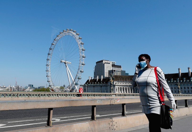 A woman wearing a protection mask walks over Westminster Bridge in London, Wednesday April 22, 2020 during the COVID-19 lockdown. (AP Photo/Frank Augstein)