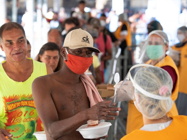 Volunteers from a christian church give food to homeless people during a quarantine imposed by the state government to help stop the spread of the new coronavirus in Sao Paulo, Brazil, Monday, April 27, 2020. (AP Photo/Andre Penner)
